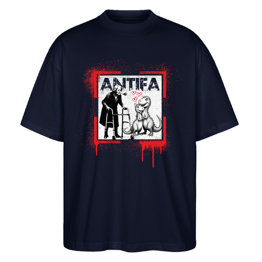 Navy unisex T‑shirt front graphic: red paint‑splatter square with dripping paint framing a person using a walker facing a seated dinosaur; pink hearts float between them and distressed white “ANTIFA” lettering appears above; organic cotton, screen‑printed protest artwork mixing street‑art aesthetics with an affectionate motif.